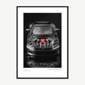 Framed print: front view of a dark supercar with carbon fibre and red lights, black wood frame