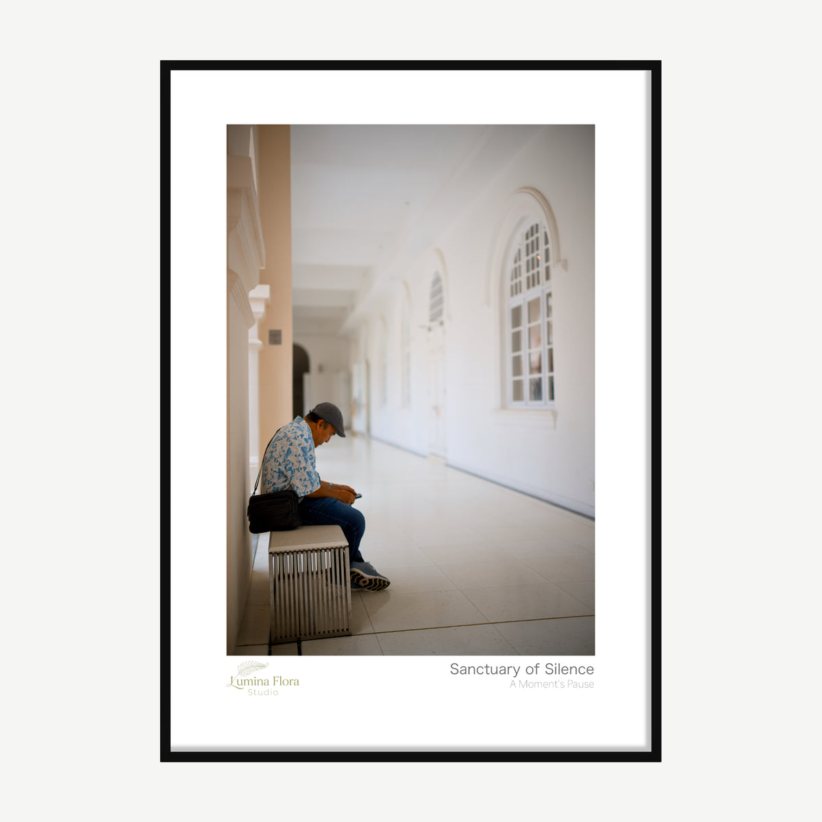Framed print: lone person seated in a bright white arched hallway, black wood frame